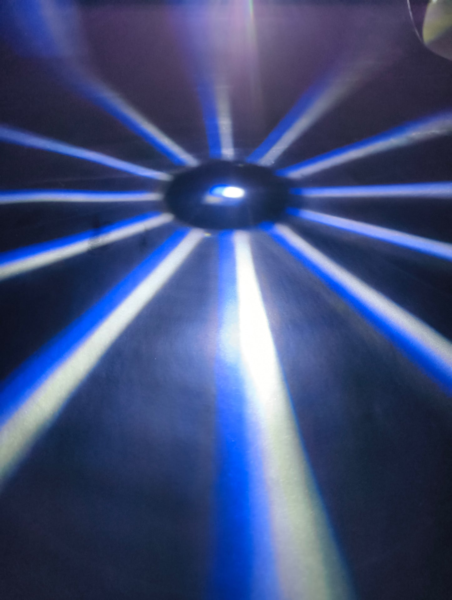 Close-up of a blue light source with concentric circular patterns on a dark background