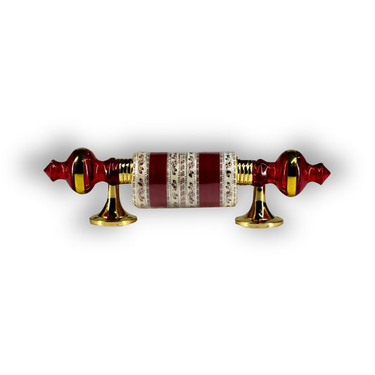 A red and gold truck decoration items which is churra accessory, featuring a beaded design with two golden knobs on either side.