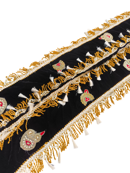 Decorative black fabric with gold embroidery and tassels on a white background